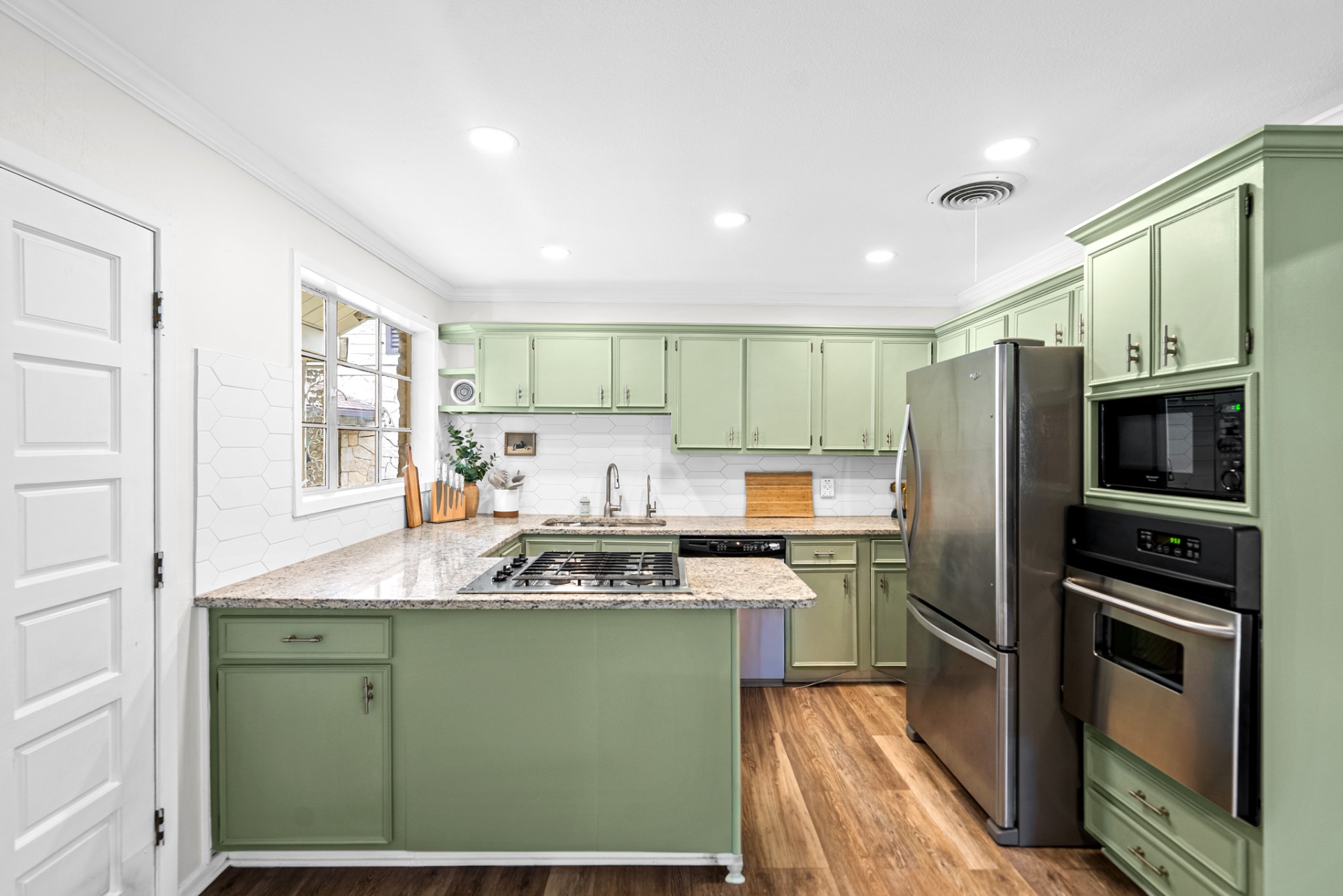 Kitchen with sage green cabinets, granite counters, stainless appliances, and gas cooktop at Casa Thorman