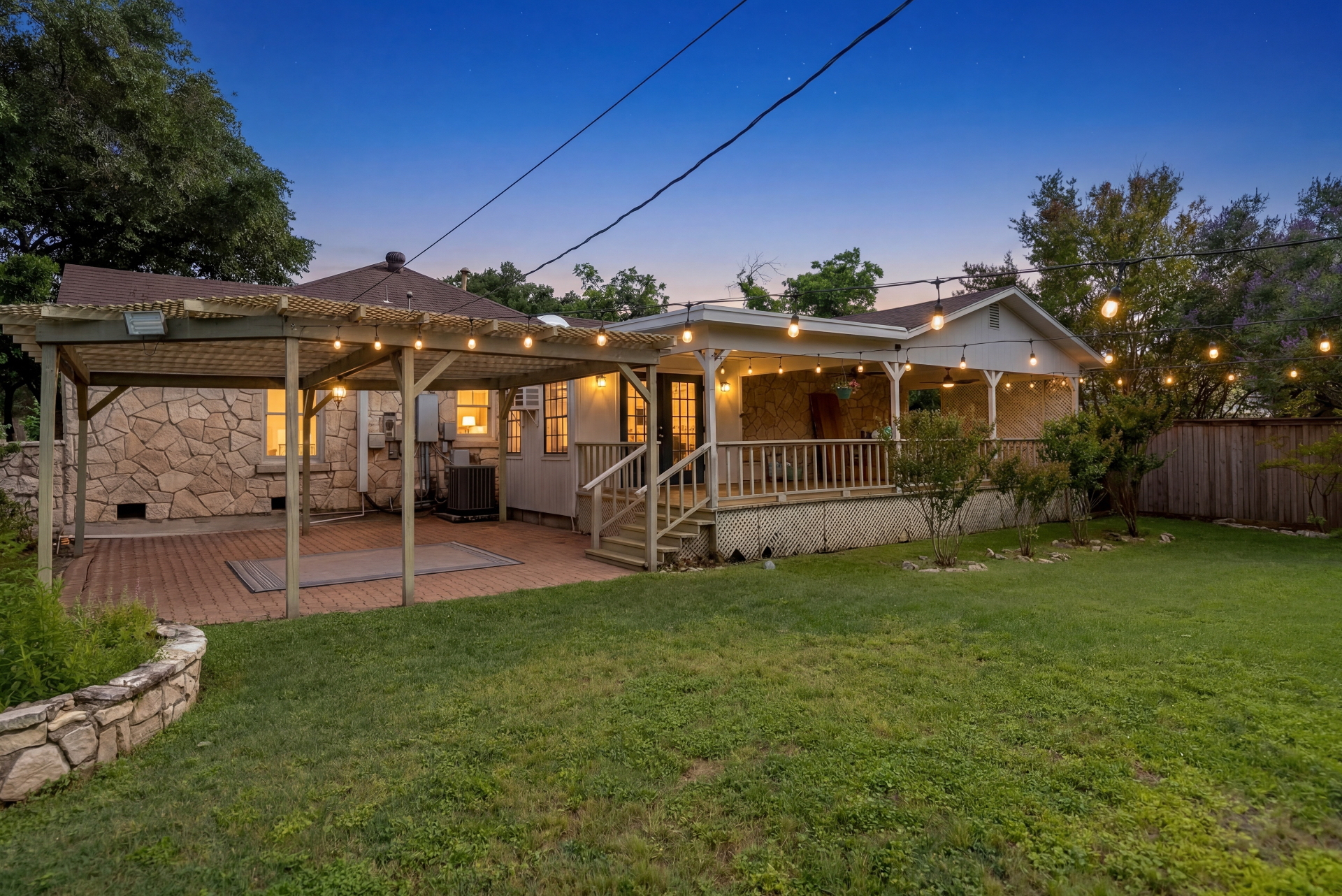 Twilight backyard view with string-lit pergola and covered deck at Casa Thorman