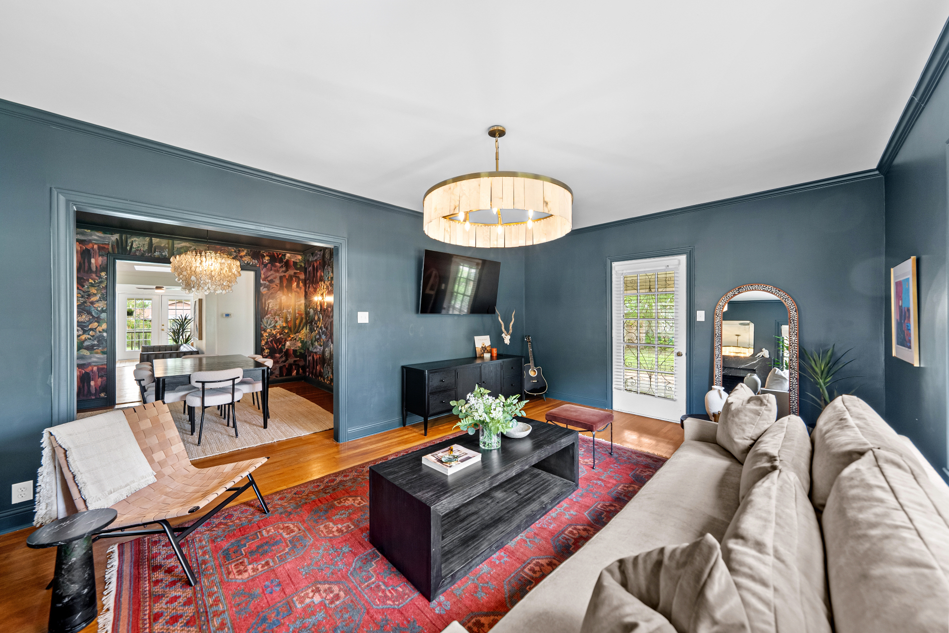 Wide living room view with navy walls, linen sofa, and dining room visible through doorway at Casa Thorman
