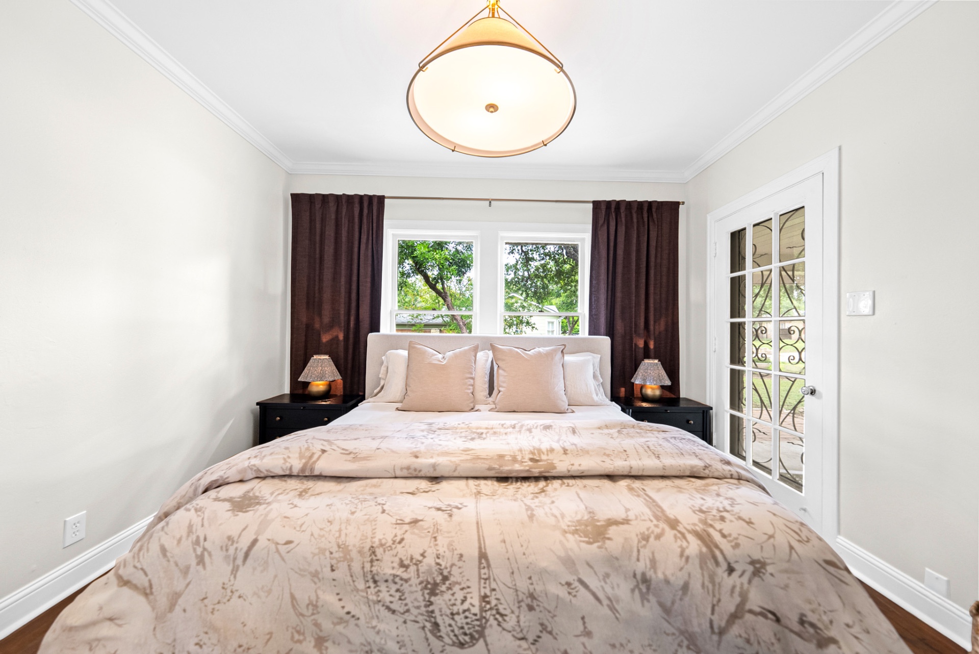 Primary bedroom king bed centered between black nightstands with brass lamps at Casa Thorman