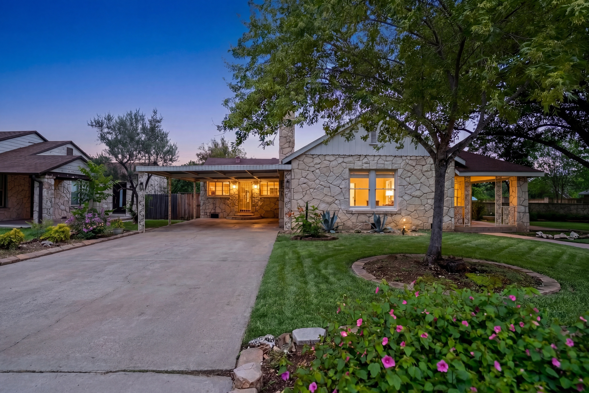 Front exterior of Casa Thorman at dusk with limestone facade and covered carport